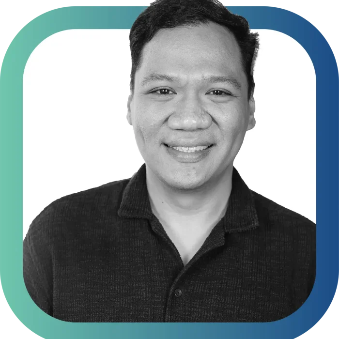 A smiling man with short, dark hair wearing a dark collared shirt, shown in a black-and-white photo with a rounded square, blue and green gradient border.